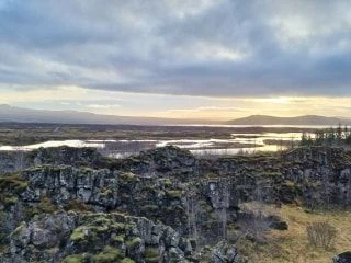 Scenic view of rocky landscape under an expansive cloudy sky at sunset.